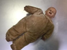 A 1930s moulded plastic headed child's muscial doll with plush body and stuffed legs (31cm x 14cm)