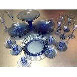 A collection of blue glass dessert plates, comport, glassware and seven candlesticks (tallest glass: