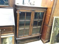 An oak bookcase, the rectangular top with antique finish and moulded edge above a carved narrow