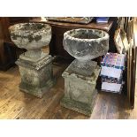 A pair of composition circular stone urns with swags and associated pedestals with laurel wreaths,