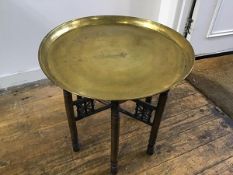 An Eastern folding stand with engraved brass circular tray, with stylised Egyptian figures and