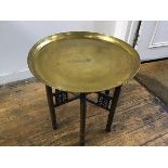 An Eastern folding stand with engraved brass circular tray, with stylised Egyptian figures and