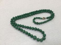 A green jadeite graduated bead necklace (largest bead approx:7mm) (l.29cm)