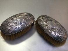 A pair of 19thc Continental white metal chased oval hairbrushes, unmarked (5cm x 13cm)