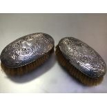 A pair of 19thc Continental white metal chased oval hairbrushes, unmarked (5cm x 13cm)