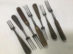 A group of three horn handled and four treen handled three prong 19thc. forks (longest: 20cm)