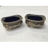 A pair of Birmingham silver salts with chased borders, complete with blue glass liners (h.3cm x l.