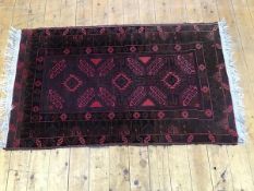 An Iranian rug, the centre rectangle with stylised triple flowerhead medallions enclosed within a