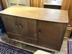 An oak Ercol sideboard, the shaped top with moulded edge above an arrangement of three panel doors