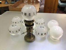 An Edwardian brass clockwork night light lamp with single hand and opaque glass globes, with roman