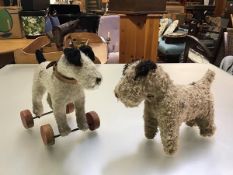 A mohair wool straw filled terrier on wheels and another similar, with inset glass bead eyes (h.24cm