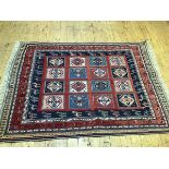 A Caucasian rug, the centre panel with four rows of four stylised flowerhead medallions enclosed