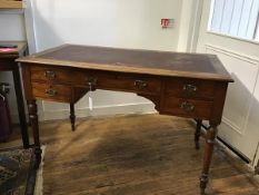 An Edwardian oak writing table,the rectangular top with inset skiver and centre frieze drawer,