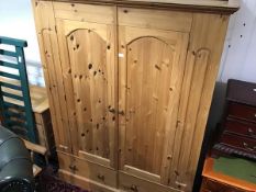 A pitch pine wardrobe with moulded cornice and arched panel doors, fitted two drawers to base (h.