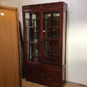 A Chinese cherrywood display cabinet, the top with moulded frieze above a pair of glazed panel doors