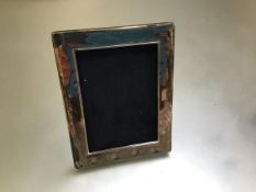 A modern silver rectangular photograph frame (16cm x 13cm outer), on hardwood easel stand (missing