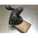 A carved grey and white soapstone abstract sculpture, possibly of an Orca, on base (h.25cm x 26cm