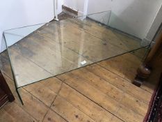 A rectangular toughened glass coffee table on moulded end supports (h.21cm x 107cm x 60cm)