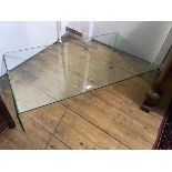 A rectangular toughened glass coffee table on moulded end supports (h.21cm x 107cm x 60cm)