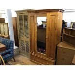 A modern pitch pine wardrobe, the moulded cornice above a centre mirror panel door and single