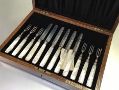 An oak canteen containing a set of six pairs of Birmingham silver engraved bladed fruit knives and