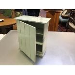 An Edwardian tongue and groove style miniature green painted cabinet with shelved interior, raised