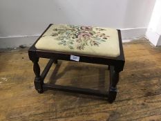 A 1920s oak stool with inset needlework machine made panel, on turned baluster supports (h.27cm x