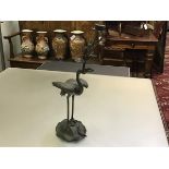 A large Japanese bronze crane candlestick, the bird holding a water lily sprig with candle holder