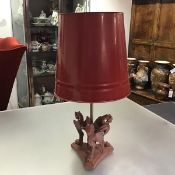 A painted cast-iron table lamp modelled as three griffins on a triform platform base issuing a brass