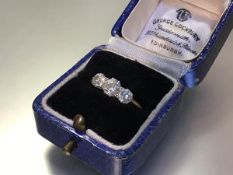 A three stone diamond ring, early 20th century, the three graduated round brilliant-cut stones on an