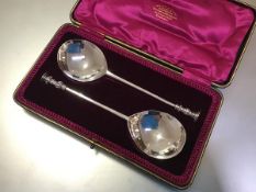 A cased pair of Edwardian silver seal-top serving spoons, Thomas Bradbury & Sons, London 1907, in