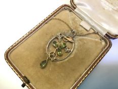 An Edwardian 15ct gold peridot and seed pearl pendant, of oval form, centred by three pear-cut