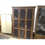 An unusual oak and carved panel wardrobe, incorporating a set of nine Chinese relief carved hardwood
