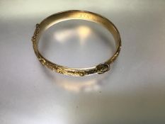 An Edwardian 9ct gold "buckle" bangle, the hinged front with buckle motif on engraved scrollwork,