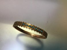 A 9ct gold hinged bangle set with turquoise and seed pearls, c. 1900, the front with a line of