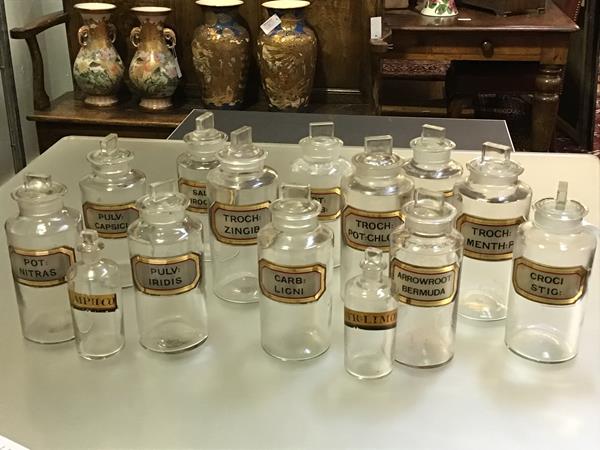 A group of late 19th century clear glass pharmacy jars each with red and gilt label, twelve of