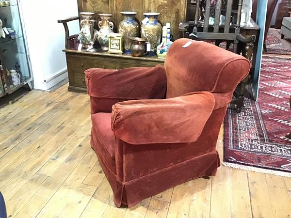 A small upholstered club chair, early 20th century, with outscrolled arms flanking a loose-cushioned