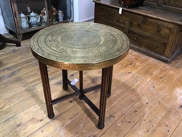 A Moorish brass tray table, the circular top with Islamic script and decoration, raised on a folding