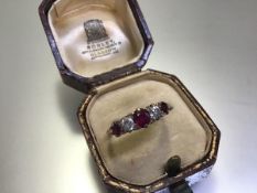 A ruby and diamond five-stone ring, early 20th century, scroll-claw set with three graduated round-