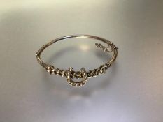 A seed pearl set yellow metal hinged bangle, early 20th century, unmarked, mounted with a