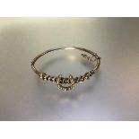 A seed pearl set yellow metal hinged bangle, early 20th century, unmarked, mounted with a