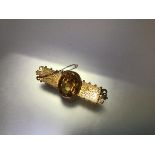 A late Victorian citrine brooch, the large oval-cut stone within a beaded mount, on a foliate-scroll