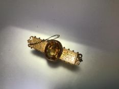 A late Victorian citrine brooch, the large oval-cut stone within a beaded mount, on a foliate-scroll