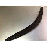 An Aboriginal war boomerang, carved to one side with a sinuous snake-like design. Length 74cm