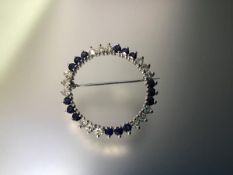 A diamond and sapphire brooch, of hoop form, mounted with bands of three round brilliant-cut