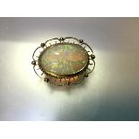 An opal brooch, the large oval opal within a gold wirework frame indistinctly stamped "18ct", with