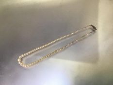 An emerald and diamond mounted single strand cultured pearl necklace, the graduated strand on an