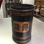 A black japanned metal canister, of cylindrical form, painted with a panel of Oriental calligraphy