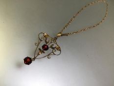 A ruby pendant in the Art Nouveau taste, of open wirework, claw-set with two round-cut rubies and