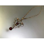 A ruby pendant in the Art Nouveau taste, of open wirework, claw-set with two round-cut rubies and